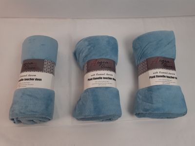 trois couvertures bleues enroulées posées sur une table blanche