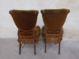 pair of brown velvet chairs with fringes on them against a white wall