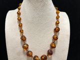 a necklace made of glass beads on a white mannequin