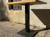 a wooden table with a metal base on a sidewalk