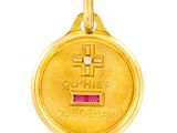 a close up of a gold medal with a red stone