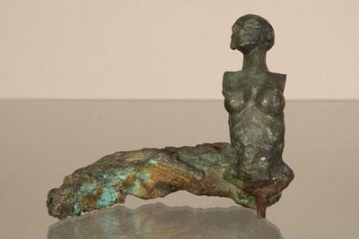 statue d'une femme assise sur un rocher posé sur une table en verre