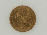 a gold coin with a rooster on it on a white surface