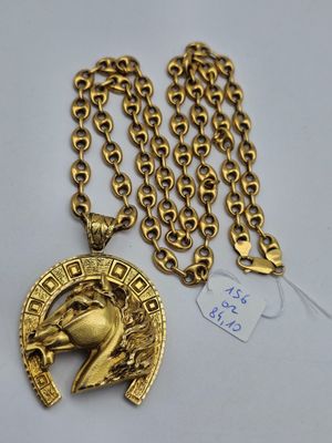 un gros plan sur un collier en or orné d'une tête de cheval