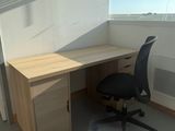 a computer desk with a chair in front of a window