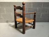 a wooden chair with a wicker seat on a cement floor