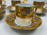 five cups and saucers with gold and blue designs on them