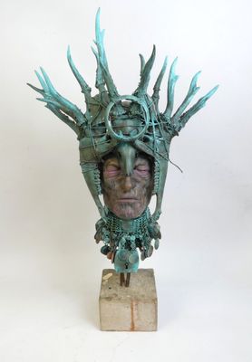 sculpture of a man ' s head with horns on a wooden base