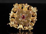 gros plan d'une bague en or avec une pierre rouge au centre