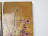 two paintings of flowers on the wall of a room
