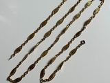 a close up of three gold chains on a white surface