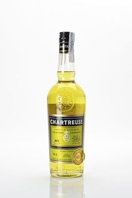 une bouteille de whisky à la Chartreuse posée sur une surface blanche