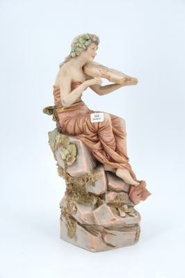 figurine of a man sitting on a rock playing a flute