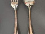 two silver spoons and a fork on a table