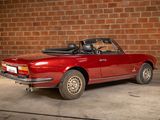 a red convertible car parked in front of a brick wall