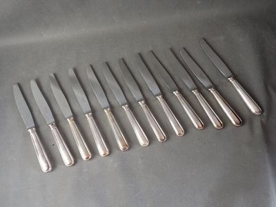 six silverplated knives are lined up in a row on a table
