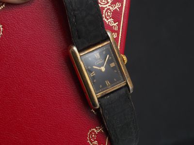 une femme tenant une montre à son poignet, avec un livre rouge en arrière-plan