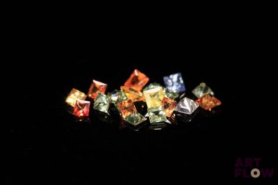 un gros plan sur un assortiment de diamants de différentes couleurs posés sur une surface noire