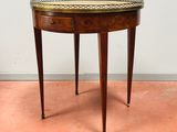 une petite table ronde au plateau doré, posée sur un sol rose