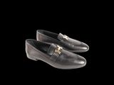 black leather loafers with gold buckles on a black background