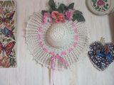un chapeau blanc orné de fleurs roses, à côté d'autres objets