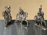 three figurines of men riding on horses on a table