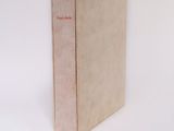 an old book sitting on top of a white table next to a white wall