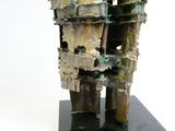une sculpture représentant un bâtiment, réalisée en métal et posée sur un socle noir