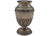un vase en argent posé sur une surface blanche