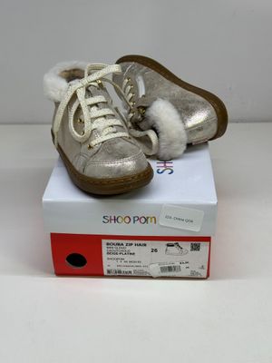 une paire de chaussures argentées posées sur une boîte, sur une surface blanche