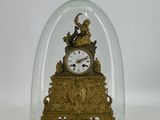 une horloge en or sous un dôme de verre sur une table