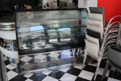 des tables et des chaises dans un restaurant au sol à carreaux et doté d'une vitrine