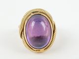 a gold ring with a purple stone in the center