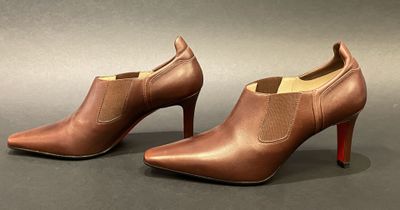 a pair of brown leather ankle boots with red soles