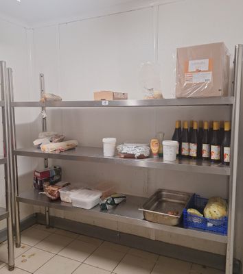 une étagère en métal sur laquelle sont posées des bouteilles de vin et d'autres produits alimentaires