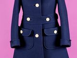 un manteau bleu posé sur un mannequin, devant un fond rose