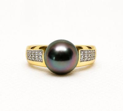 a close up of a black pearl and diamond ring on a white surface