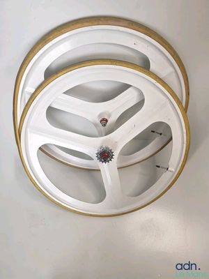 un gros plan d'une roue blanche et dorée sur un mur blanc