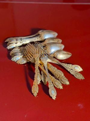 a red table with a bunch of silver spoons and spoons on it