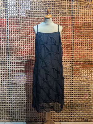 a black dress on a mannequin mannequin stand in front of a wall