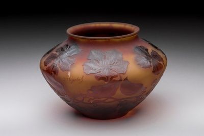 a brown vase with leaves on it sitting on a table