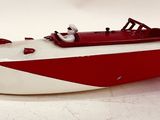 a red and white toy boat on a white surface