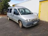 une camionnette argentée garée sur un parking à côté d'un immeuble jaune