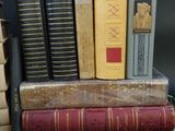 a stack of books sitting on top of a table next to a pile of books