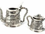 two silver teapots sitting next to each other on a white surface