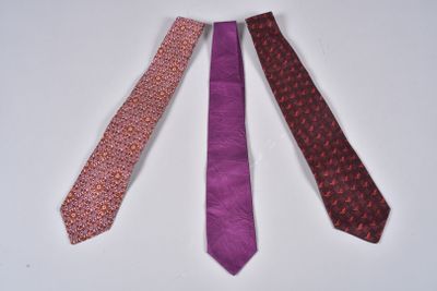 three different colored ties laid out on a white surface