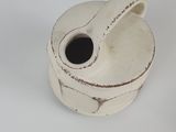 a white vase with a black handle on a white surface
