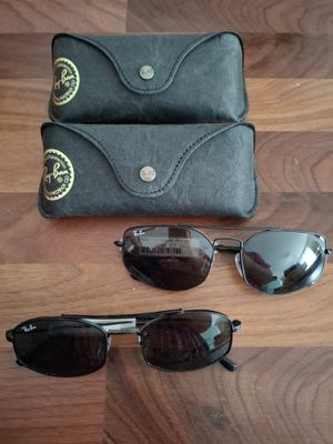 deux paires de lunettes de soleil et un étui posés sur un plancher en bois
