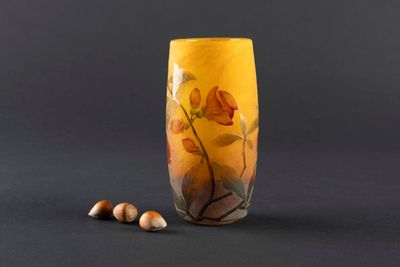 a yellow vase with flowers and nuts on the table