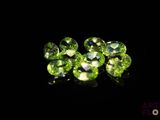 a close up of a bunch of green gems on a black surface
